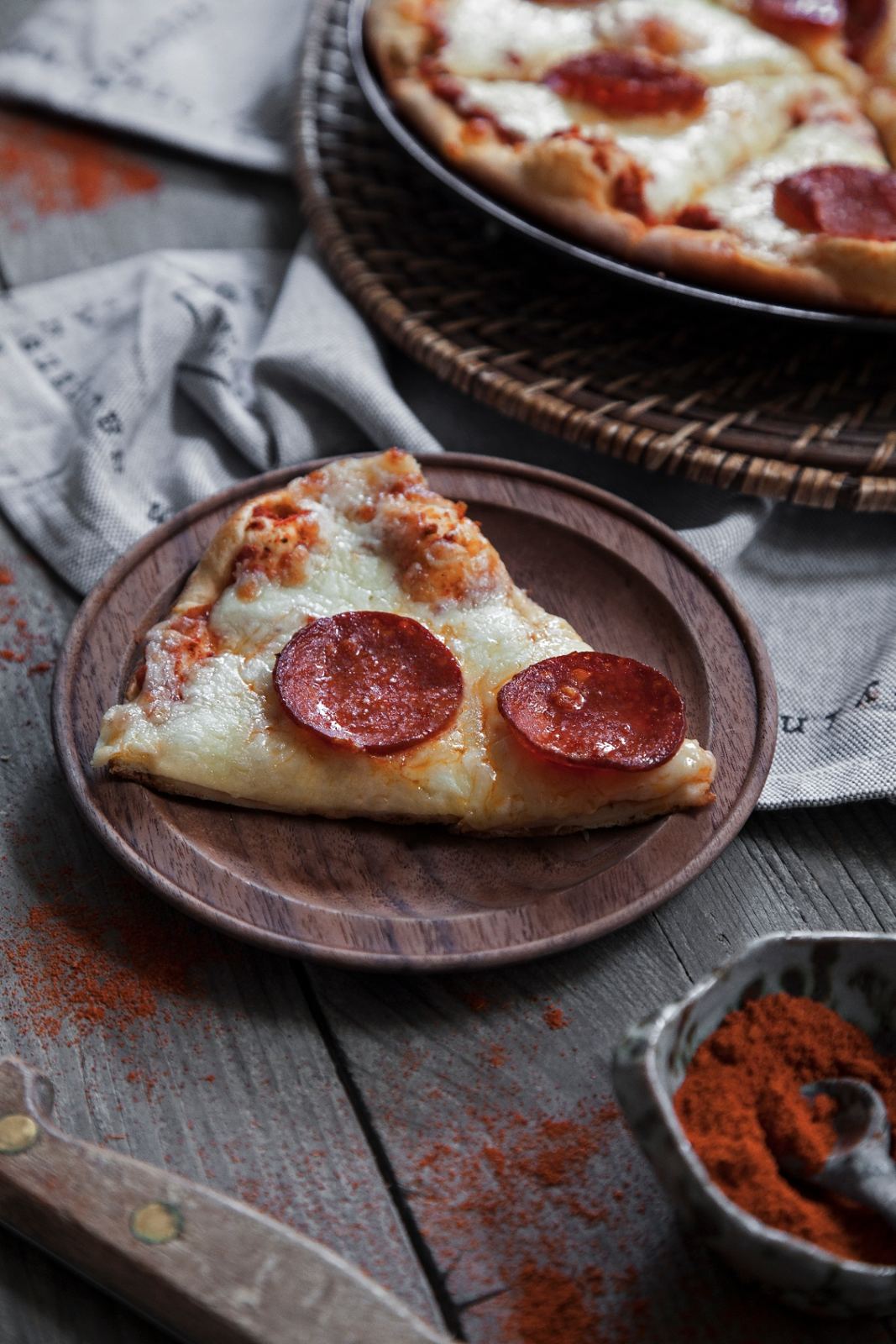 A slice of pepperoni pizza on a wooden plate